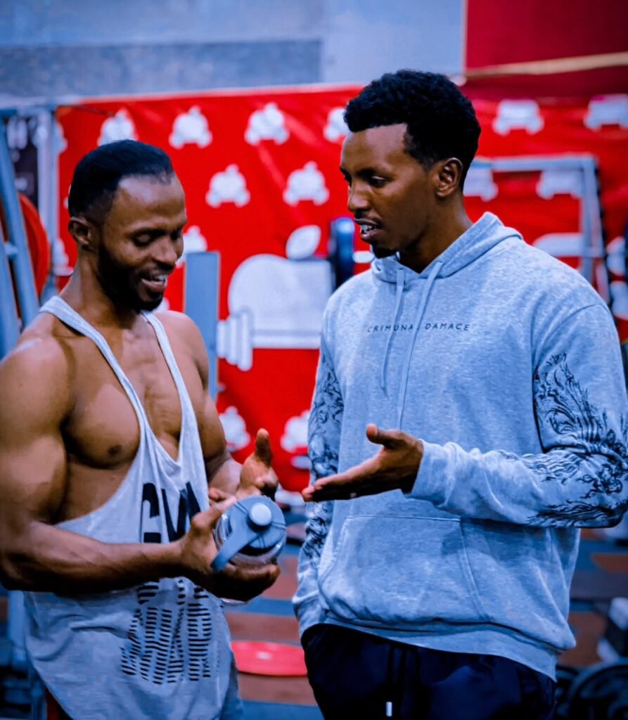Fitness coach in a gym talking with a young man in a grey hoodie