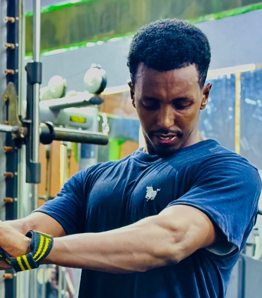 Young man in a navy T-shirt training on gym equipment